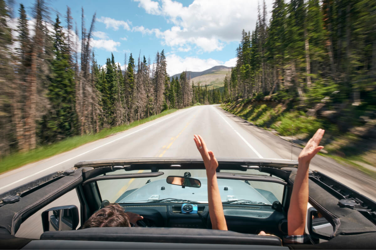 Driving a Jeep in the Colorado mountains with the top down and passenger hands poking out of the vehicle
