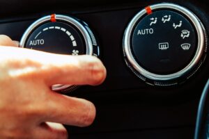 closeup of a hand adjusting the temperature controls in a car