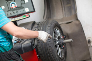 car tire being balanced by a mechanic on wheel balancing machine
